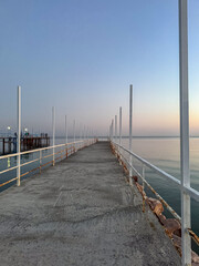 Fototapeta premium Pier at Issyk Kul Lake in Kyrgyzstan during calm evening. Minimal composition, smooth water surface and pastel sky tones.