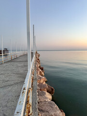 Fototapeta premium Pier at Issyk Kul Lake in Kyrgyzstan during calm evening. Minimal composition, smooth water surface and pastel sky tones.