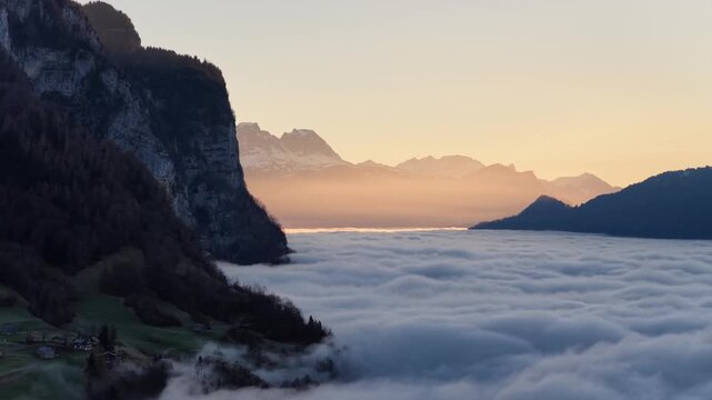 Aerial drone view of mountain cliffs rising above clouds at Walensee Switzerland