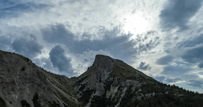 Aerial hyperlapse showcases the Fuorn Pass Ofen Pass in Graub&uuml;nden Switzerland highlighting the high alpine mountain landscape under a cloudy sky with sunlight.