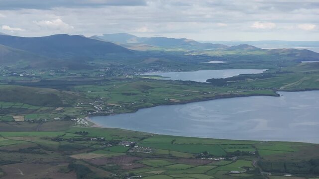 Breathtaking drone footage capturing the lush green landscape of the Dingle Peninsula, featuring Ventry Bay and distant mountains under a cloudy Irish sky.