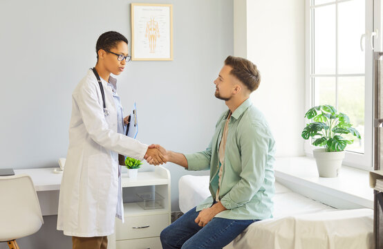 Clinic room meeting, female doctor shaking hands with male patient sitting on examination bed, professional greeting, welcoming medical environment, trust between healthcare provider and client