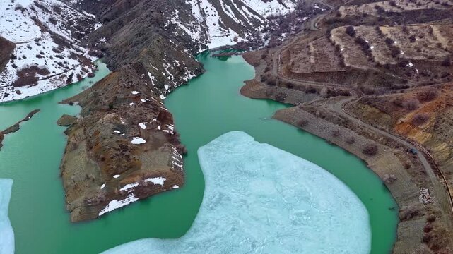 Drone Flight Over Mountain Lake with Floating Ice and Snowy Hills
