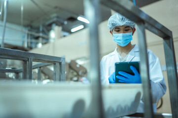 Seafood processing technician analyzes batch information on handheld device during routine quality audit in industrial plant, emphasizing structured documentation system. © Wanwajee