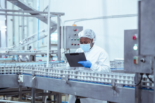 Production worker reviews packaging consistency of metal cans in automated food factory, recording results to support traceability system and operational transparency.