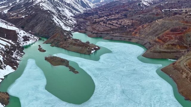 Wide Aerial View of Frozen Reservoir Between Snow Covered Mountains