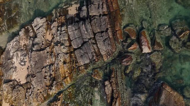 Cinematic slow ascent revealing the patterns of a rocky shore. Transparent ocean water washing over ancient stones on a tropical coast. Beautiful natural background. Sri Lanka 4K