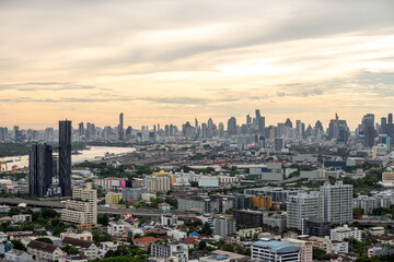 Obraz premium Expansive urban skyline with dense high-rises and a winding river under a cloudy evening sky, showcasing a sprawling modern cityscape. Bangkok, Thailand