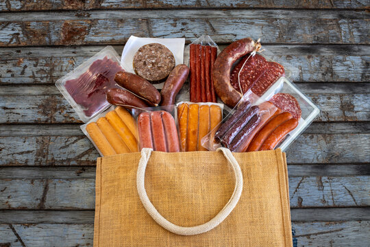 Vacuum sealed dried meats in the paper shopping bag.  Shopping from delicatessen concept. 