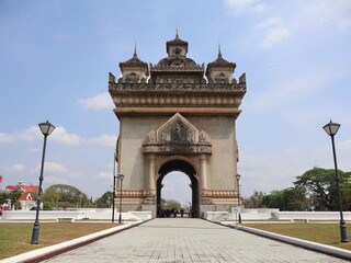 Fototapeta premium VIENTIANE, LAOS - FEBRUARY 25, 2026: The iconic Patuxay Victory Gate monument under a blue sky with tourists visiting.
