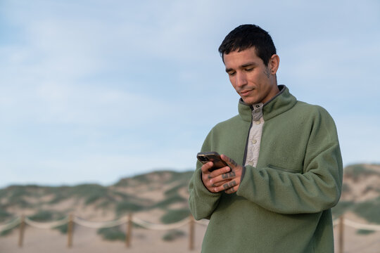 Young man using smartphone on sandy dunes