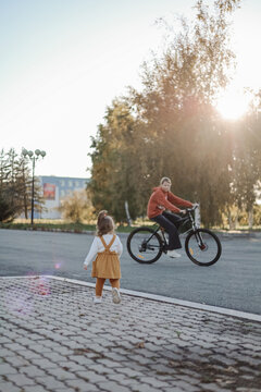 Happy toddler running ahead of smiling big sister on bike