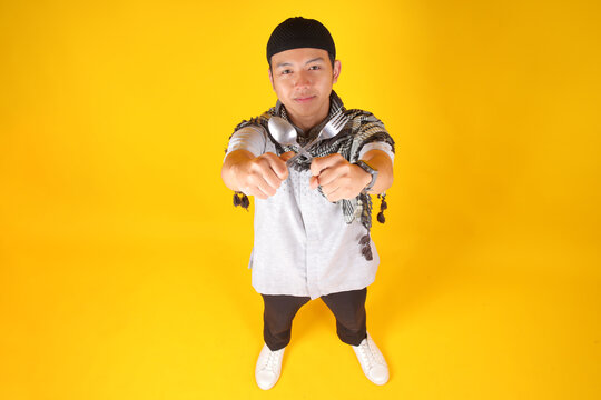 High Angle Of Asian Muslim Man Showing Spoon And Fork Waiting For Iftar Time On Yellow Background