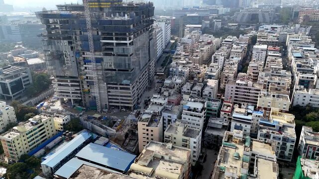 Construction of modern office towers, business parks, and developing infrastructure near residential area, reflecting Hyderabad&rsquo;s rapid digital growth set against a vast metropolitan horizon.
