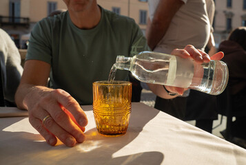 nalewanie wody do szklanki przy stoliku w restauracji w słoneczny upalny dzień © siwyk