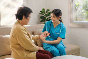 Obraz premium Young nurse providing compassionate home care, checking an elderly woman's pulse in a comfortable living room setting