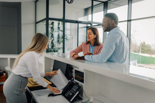 Business people engaging with a receptionist at office desk