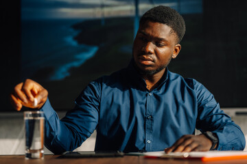 Young man taking medicine for fatigue at work