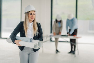 Female architect professional holding blueprints on construction site