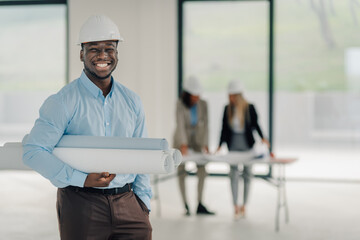 Smiling architect holding blueprints at construction site