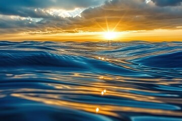 Waves reflect sunset light over the ocean with clouds above and sun shining in the evening sky