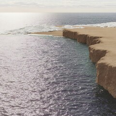 Sparkling coastline at noon with bright sun reflecting off the calm sea and sandy cliffs