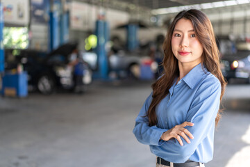 Fototapeta premium Confident asian business woman owner standing with arms crossed in auto repair shop garage, Female manager smiling at car service center, Automotive industry, mechanic and small business concept