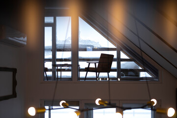 Cozy lobby of a mountain lodge with a snowy scene on its windows.