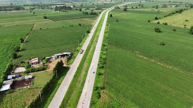 Drone aerial view of rural farmland with country road crossing agricultural fields. Countryside landscape showing agriculture