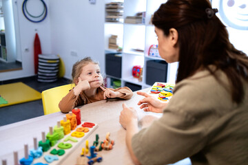 Child receiving speech therapy, a female therapist helping a little girl with communication development and language skills at a clinic for kids with speech impediment