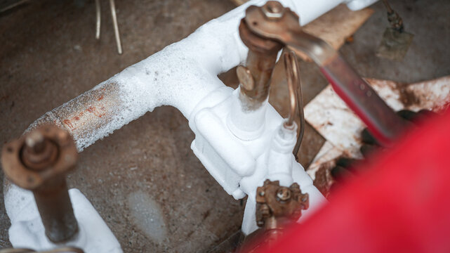 Liquid nitrogen, cryogenic chemical is flowing in rigid pipeline during transfer process. It is very super cooling temperature, cause iced frost on the pipeline surface during pumping. Close-up and se
