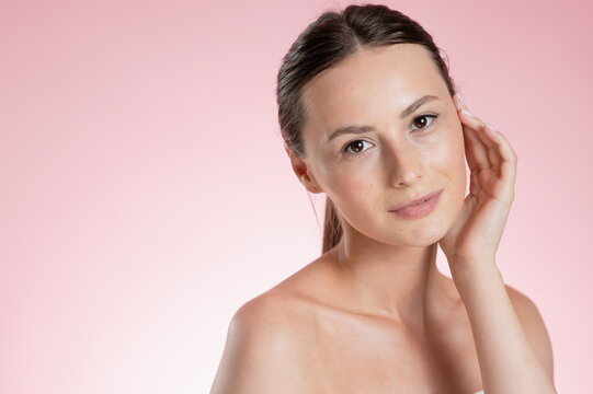 Portrait Woman with clear glowing skin on soft pink background