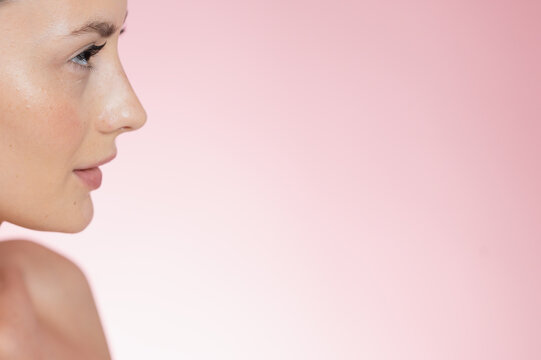 Portrait Woman with clear glowing skin on soft pink background