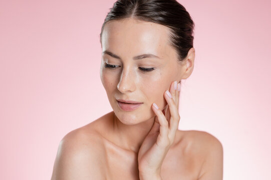 Portrait Woman with clear glowing skin on soft pink background