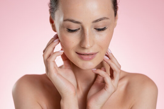 Portrait Woman with clear glowing skin on soft pink background