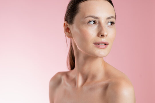 Portrait Woman with clear glowing skin on soft pink background