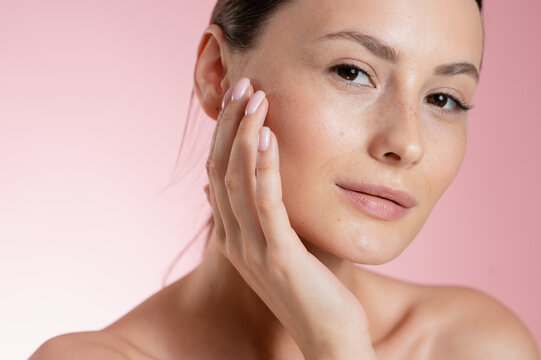 Portrait Woman with clear glowing skin on soft pink background