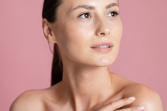 Portrait Woman with clear glowing skin on soft pink background