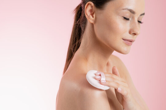 Woman applying powder puff to her shoulder for a flawless skin finish