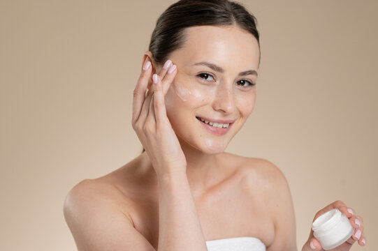 Brunette Woman skincare routine at beige studio background
