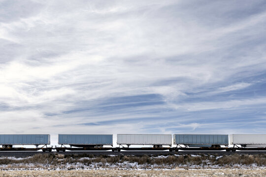 Semi trailers being moved by railcars under cloudy skies