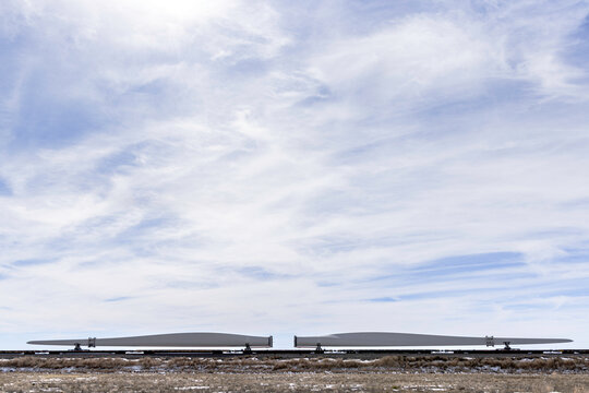 Windmill blades transported by railcar under cloudy sky