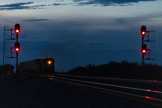 Distant trains approaches in near dark blue hour