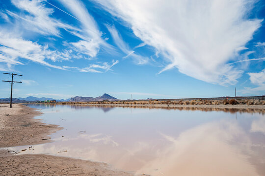 Large puddle reflecting sky distant mountains train approaching