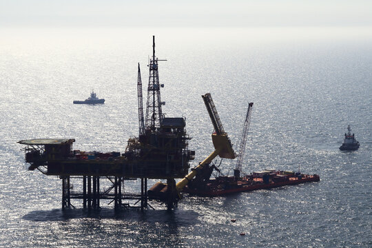 Netherlands, Netherlands - 13 February 2026: Aerial view of a colossal oil rig piercing the endless, shimmering expanse of the sea, its steel frame a stark contrast against the water.