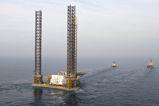 Netherlands, Netherlands - 13 February 2026: Aerial view of a towering, monolithic jack-up rig piercing the serene sea, flanked by escort vessels in a dance of maritime industry.