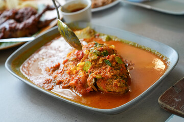 Fototapeta premium Traditional Indonesian Ikan Pesmol Fried Fish with Spicy Turmeric Sauce and Petai Beans.