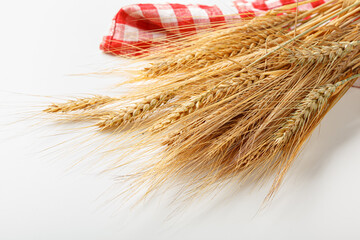 Fototapeta premium Wheat stalks arranged with a red and white checkered cloth in a simple setting