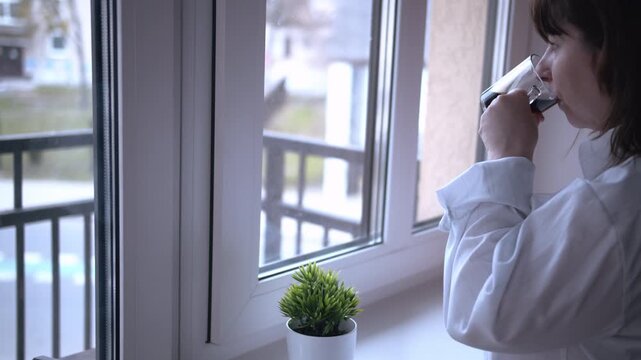 Woman Finding Joy in a Coffee Break by the Window on a Dull, Overcast Day