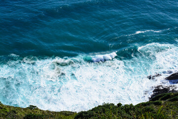 Obraz premium Aerial view of a giant ocean wave crushing onto the shore. Top down photo of turquoise sea water surface. White foam waves texture as natural background